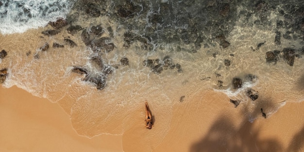 Top Aerial View van Gebrande Vrouw in Bikini op het Rocky Beach op Zomer Weekend Vakantie