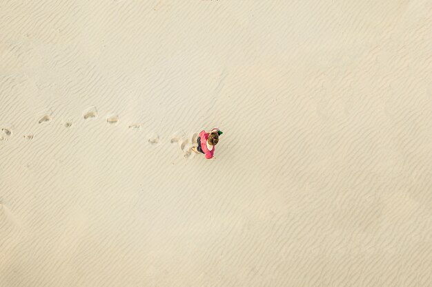 Top aerial view of young lonely man walk in desert on the sand texture. lost concept