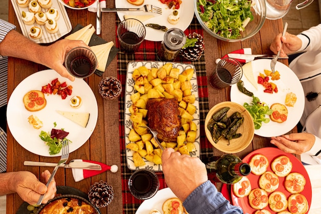 鶏肉やテーブルの真ん中から食べ物を食べたり取ったりする人々のグループのような食べ物でいっぱいの大きな木製のテーブルの上面図と上面図