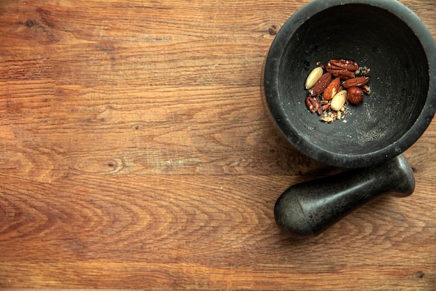 Top angle view of various nuts in stone mortar on a wooden shelf background almonds hazelnuts walnut