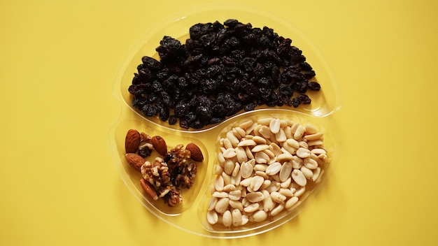 Top closeup view of delicious nuts in plastic transparent containers on yellow background