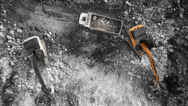 掘削機が粉された岩土を装着するティッパートラックの上から下の空中写真