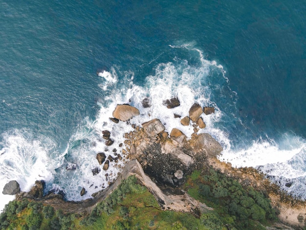 Top down aerial view of giant ocean waves crashing and foaming in coral beach