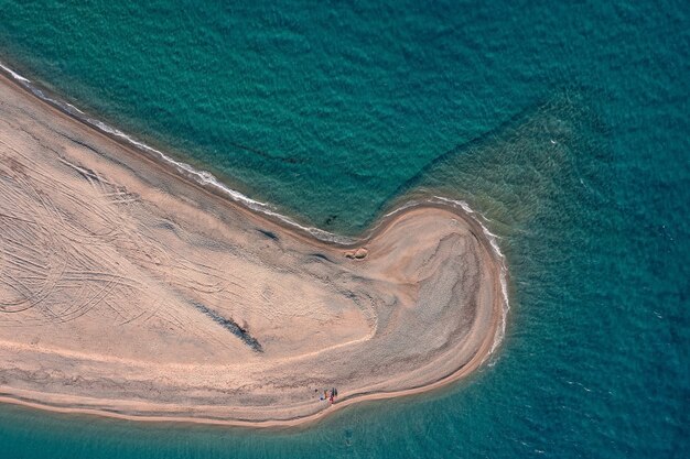 Top down aerial view of a long narrow sandy beach stretched into the turquoise sea