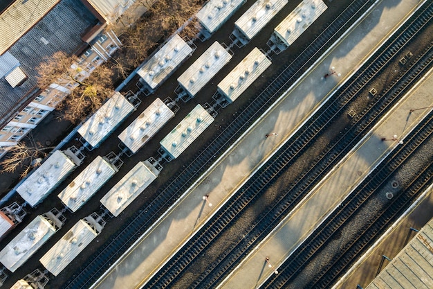 Top down aerial view of many cargo train cars on railway tracks.