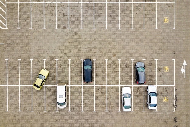 Top down aerial view of many cars on a parking lot of supermarket or on sale car dealer market.