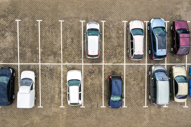 Top down aerial view of many cars on a parking lot of supermarket or on sale car dealer market.