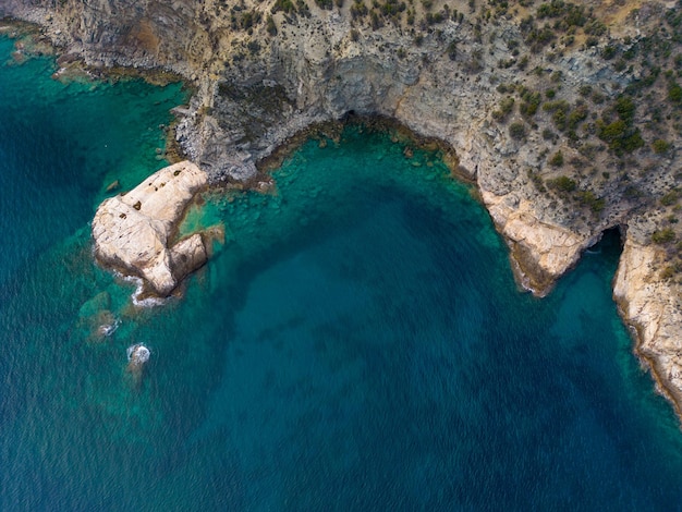 A top down aerial view of rocks and sea provides a stunning visual perspective of the rugged coastline and the mesmerizing interplay of land and water