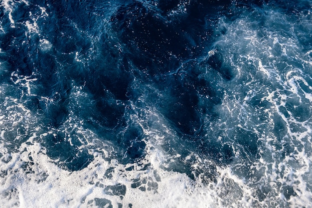 Photo top down aerial view of sea water surface. white foam waves texture as natural background.