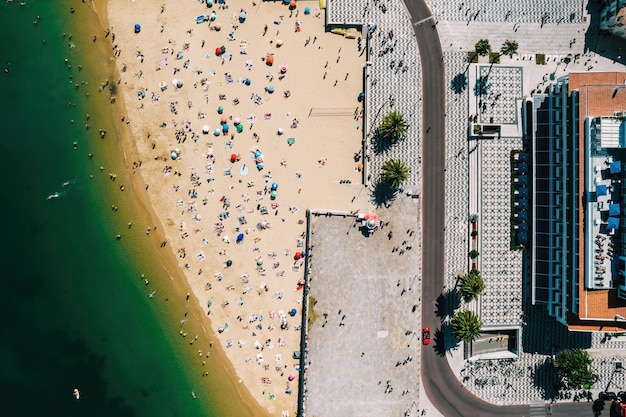 Top-down drone-weergave van Ribeira Beach in Cascais Portugal op een zomerdag met veel mensen op het strand