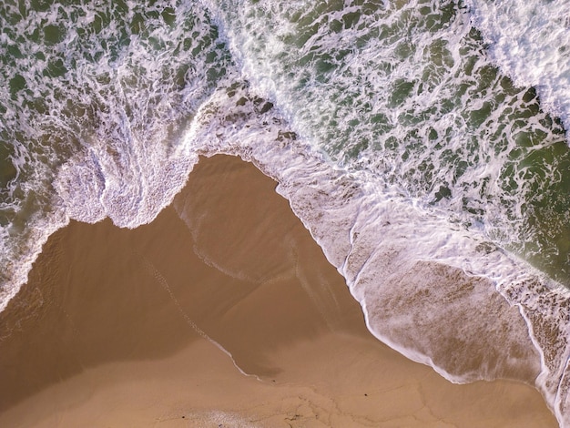 Top-down luchtfoto op een zandstrand met zee surfen niemand