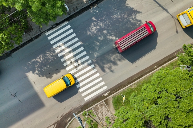 Top-down luchtfoto van drukke straat met rijdend autoverkeer en zebrapad voetgangersoversteekplaats.