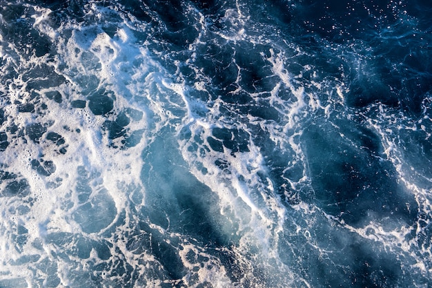 Top-down luchtfoto van zeewateroppervlak. De witte textuur van schuimgolven als natuurlijke achtergrond.