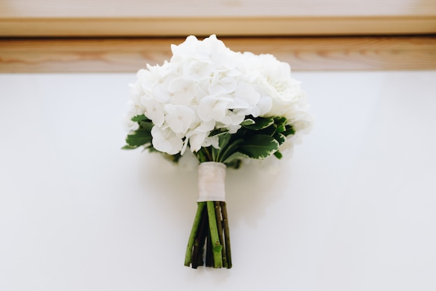 A top-down picture of a hydrangea wedding bouquet on a window-sill