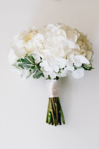 A top-down picture of minimalistic wedding bouquet of white hydrangea 