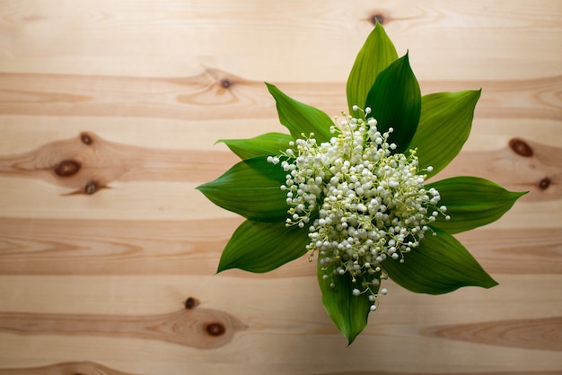 Top-down shot of beautiful bouquet of lily of the valley on old wooden table