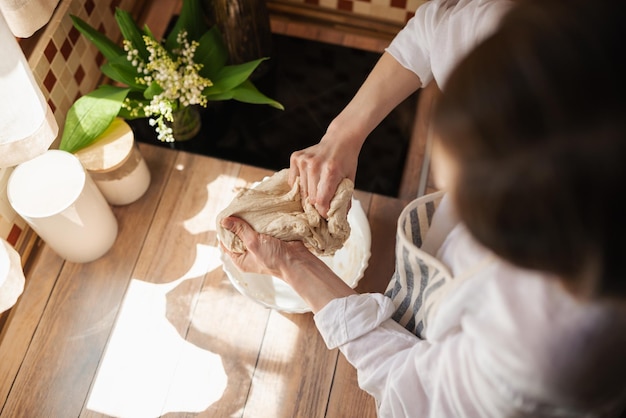 写真 自家製パンを焼くために生地を徹底的にこねる女の子ホステスのトップダウンショット