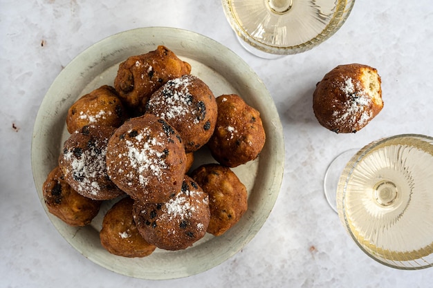 Top down view of a bowl of oliebollen translation Dutch dough fritters with a glass of champagne