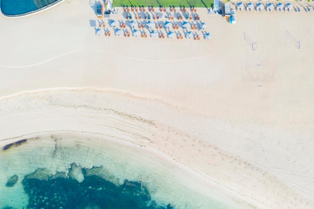 Top down view of deserted Nusa Dua beach with empty wooden deck chairs and umbrellas due to coronavirus pandemic in Bali Indonesia