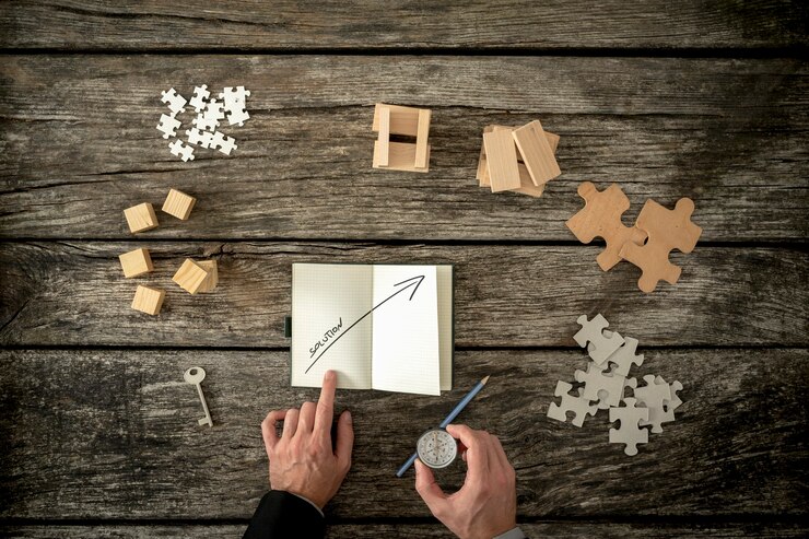 Photo top down view of hands using a compass and pointing at booklet