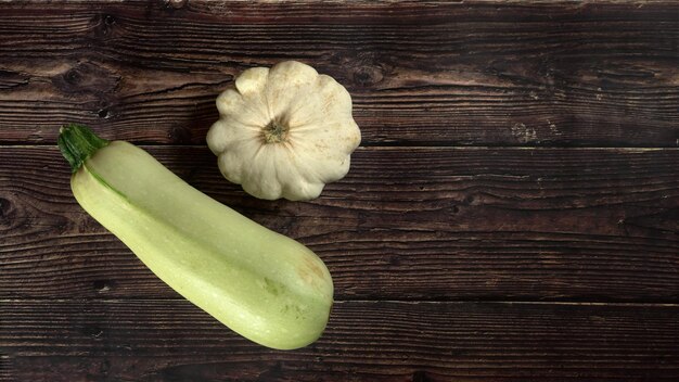 Photo top down view, pattypan squash and zucchini on dark wooden board, wide banner, space for text right side