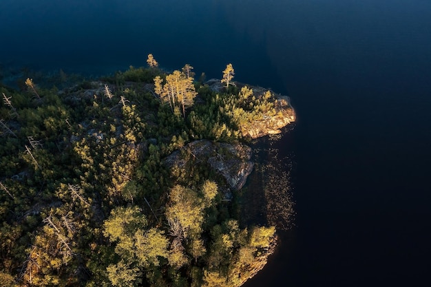 Top down view of tree covered rocky island on Lake Ladoga illuminated by rising sun Karelia Russia