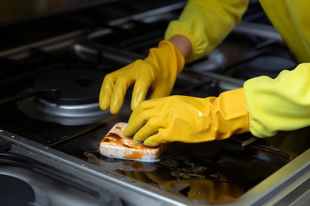 Top down view Womans gloved hand scrubs stove finding joy in post cooking cleaning