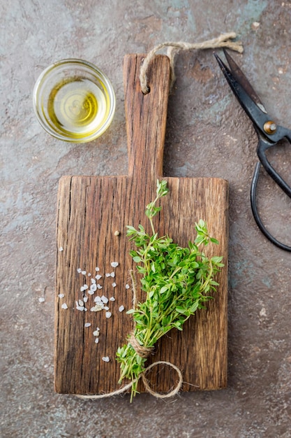 Top flat view of ingredients: salt, thyme and olive oil on dark rustic table. Cooking concept