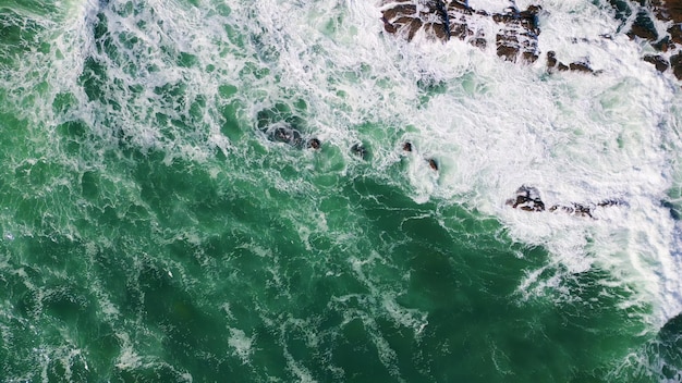 Top foaming stormy waves splashing on coastal stones drone beautiful ocean