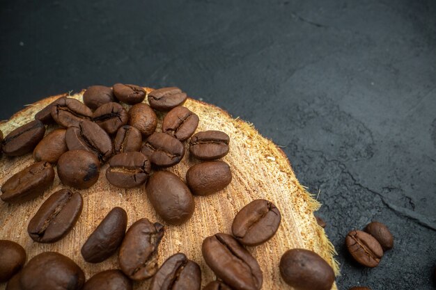 top half view roasted coffee seeds on wood board on dark background