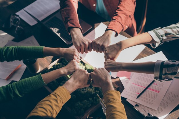 Top above high angle view cropped  marketers partners put fists together round circle support start-up goals