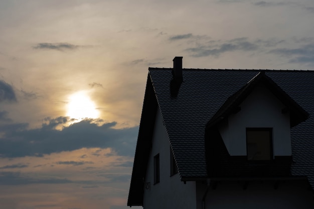 Top of the house with a roof and a loft at sunset.