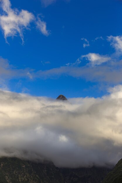 Top of the mountain above the clouds against the blue sky