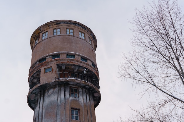 Foto cima di una vecchia torre dell'acqua malconcia contro un cielo invernale nuvoloso