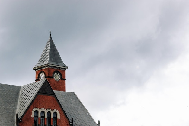 The top of an old building with a clock tower against an overcast sky