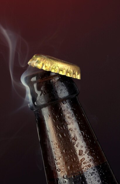 Top of open wet beer bottle on dark background