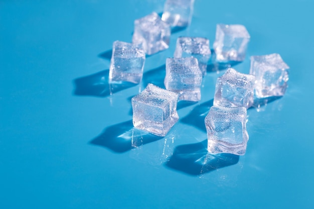 Top above overhead close up macro view photo of ice cubes and water drops on blue background