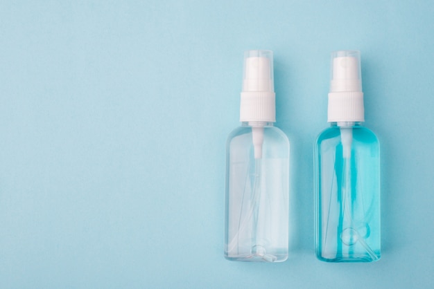 Top above overhead close up photo of two sprayers with antibacterial liquid inside isolated over pastel color blue background with empty blank space