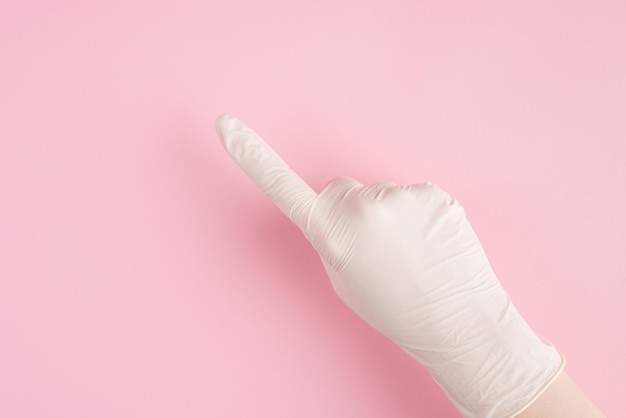 Вверху над головой крупным планом от первого лица вид от первого лица фото руки женщины-врача в перчатках, указывающей налево, изолированной на пастельно-розовом фоне с Copyspace