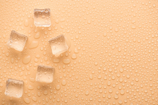 Top above overhead close up view photo ice cubes with rain drops on pastel color beige background