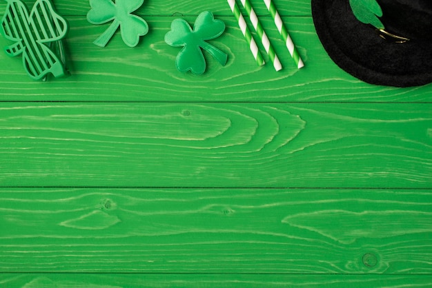 Top above overhead close up view photo picture of leprechaun black headwear drink straws clover leaves and retro disco specs isolated bright color green backdrop with blank empty space for text