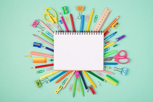 Top above overhead view photo of multicolored stationery and blank notebook isolated on turquoise background with copyspace