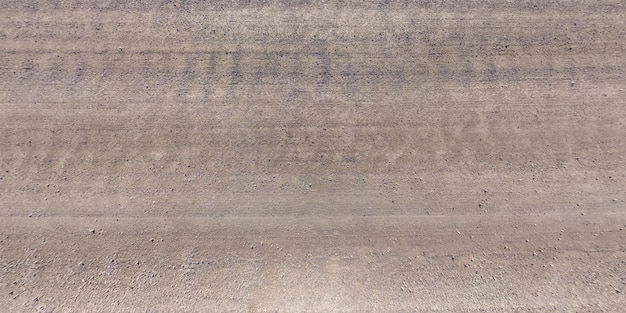 Top panorama view from above on surface of gravel road with car tire tracks