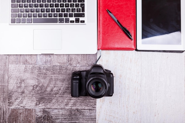 Over top photo of camera and laptop on wooden background