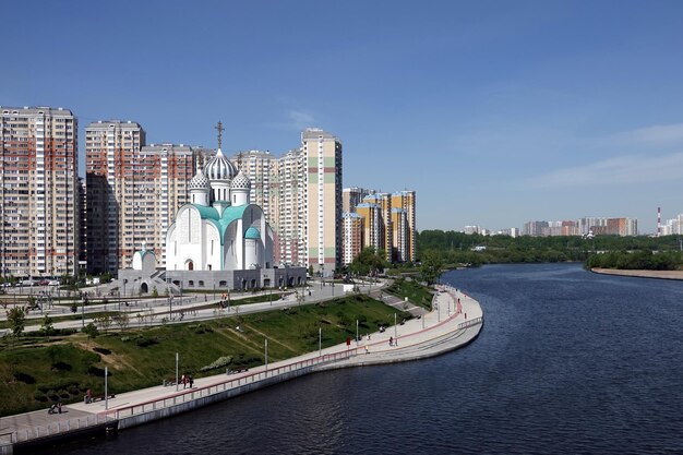 Top of Russian Christian church colored pink with cupolas with golden crosses over blue sky