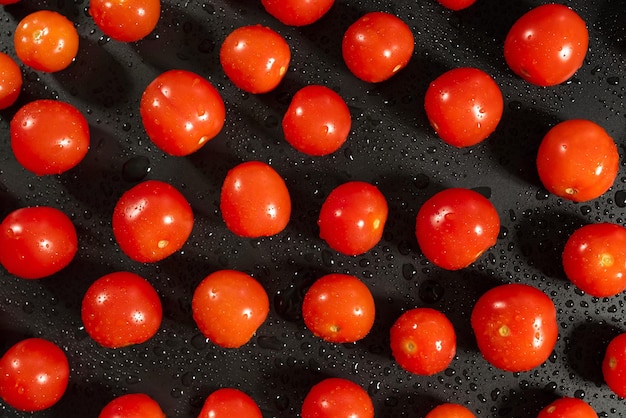 Top shot of fresh cherry tomatoes with water drops on kitchen black table