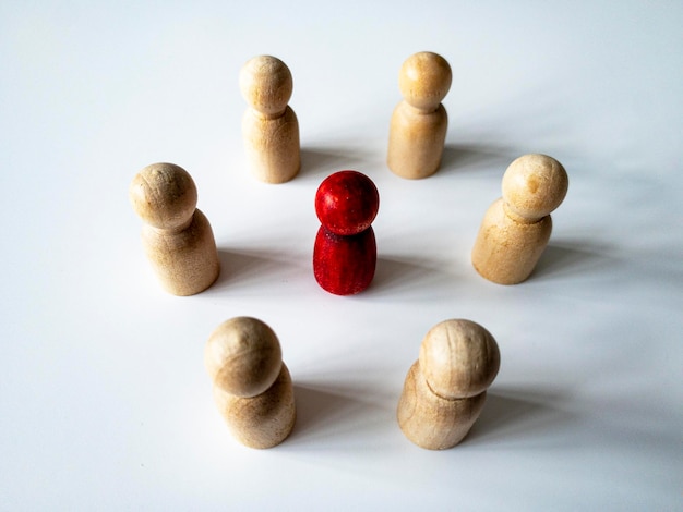 Top side view of red wooden doll figure surrounded by other doll figure Harassment and bullying concept