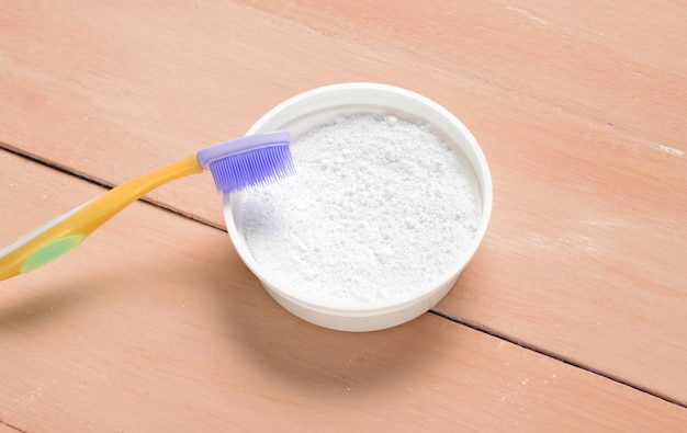 Top side view of tooth powder and a toothbrush