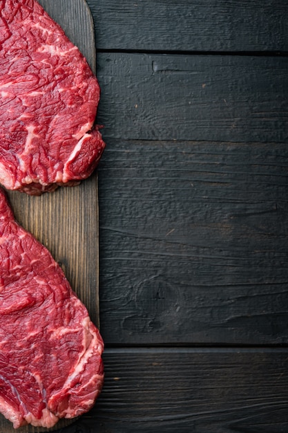 Top sirloin beef steaks cut, on black wooden table, top view,