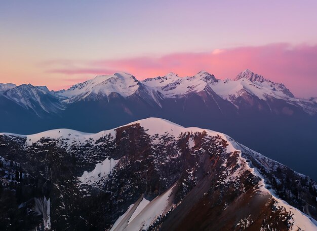 Top uitzicht op hoge bergen met sneeuwkappen op de toppen in de natuur tegen een roze mooie hemel